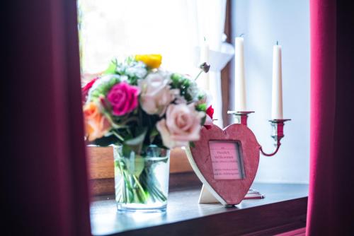 a vase of flowers and a heart on a table at Landhaus Wern's Mühle in Ottweiler