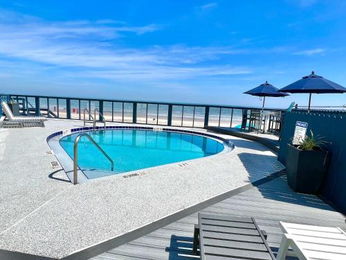 a swimming pool on a deck with the ocean in the background at Ocean Oasis - Ocean View At Symphony Beach Club in Ormond Beach