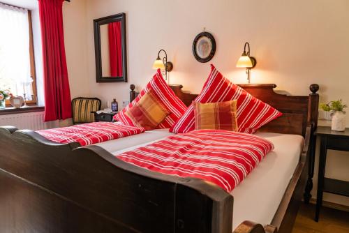 a bed with red and white blankets and pillows at Landhaus Wern's Mühle in Ottweiler