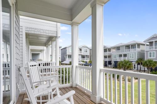 a white rocking chair on a porch with condos at Luxury Th In Emerald Isle, Nc Welevator in Emerald Isle