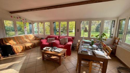 un salon avec un canapé rouge et une table dans l'établissement Gite Noisy, à Noisy-sur-École