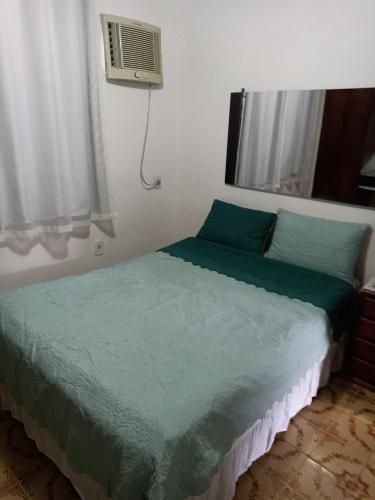 a bed with a green comforter in a bedroom at Refúgio Piratininga 202 in Niterói