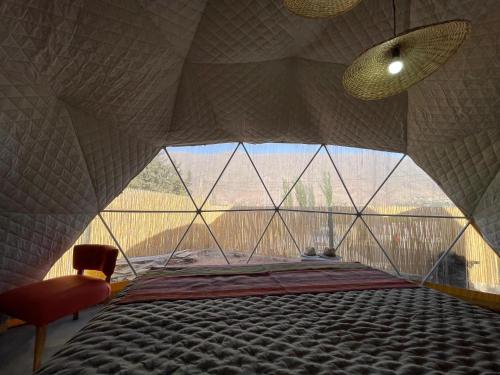 a bed in a room with a large window at Tinku Huasi Domos Suite in Tilcara