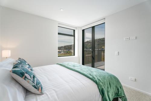 une chambre blanche avec un lit et une grande fenêtre dans l'établissement Stylish & Modern Wanaka Townhouse - Your Dream Holiday Awaits, à Wanaka