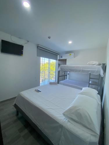 Un dormitorio con una gran cama blanca y una ventana. en Hotel Alec, en Valledupar