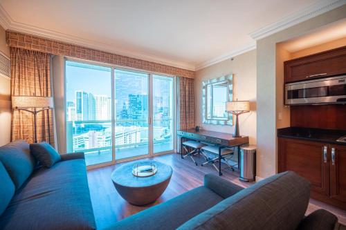 a living room with a blue couch and a desk at No Resort Fee Strip View Balcony+ Free Valet+ Pool in Las Vegas