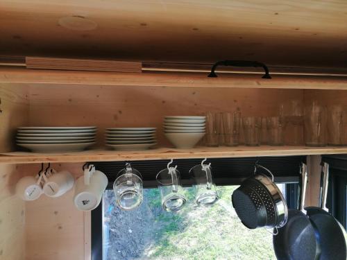 a kitchen shelf with dishes and glasses and utensils at Tiny House im Grünen in Sankt Margrethen