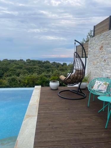 a chair sitting on a deck next to a pool at Damari Luxury Retreat Villas Skiathos in Skiathos Town