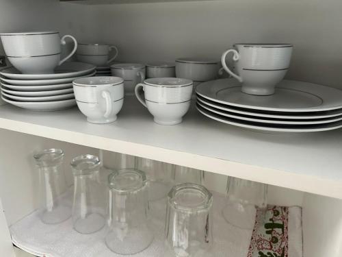 a shelf with dishes and cups and plates on it at Apartamento Top Centro de Tubarão in Tubarão