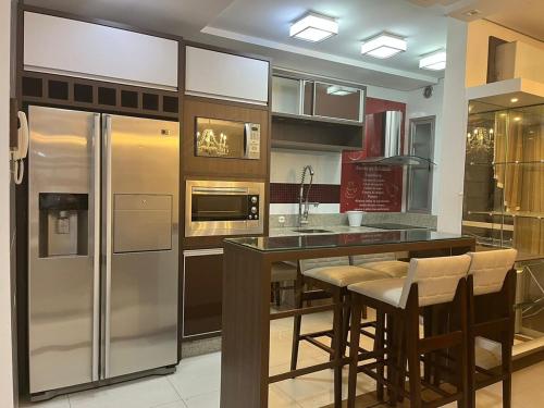 a kitchen with a refrigerator and some bar stools at Apartamento Top Centro de Tubarão in Tubarão