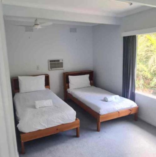 two beds in a room with a window at Scenic Hilltop Sanctuary in Upwey