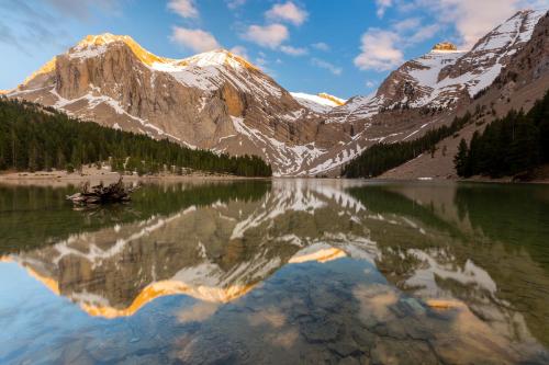 a mountain reflection in a lake with snow capped mountains at Villa de Plan Apartments&Suites in Plan