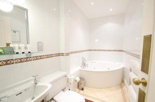 a white bathroom with a tub and a sink at The Snooty Fox in Tetbury