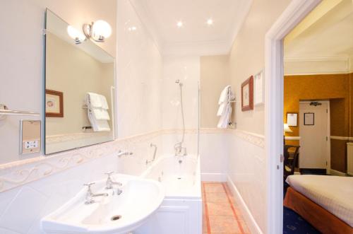a white bathroom with a sink and a mirror at The Snooty Fox in Tetbury