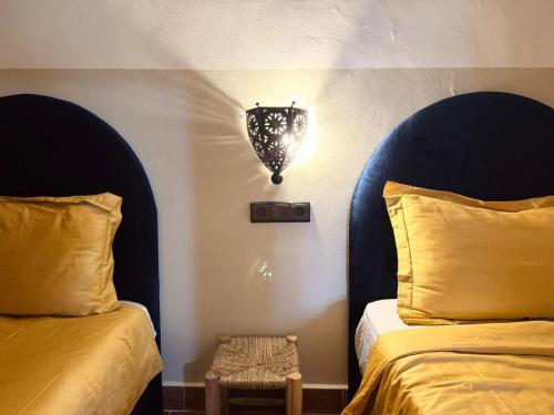 a bedroom with two beds and a light on the wall at Charming app 3 min Sania Ramel AIRPORT Tetuan in Tetouan