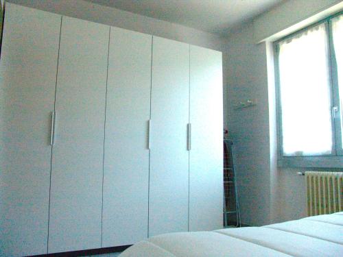 a bedroom with white cabinets and a bed and a window at Benny's Apartment Near Lake Como in Bulciago