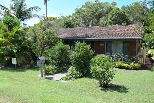 a house with bushes in front of a yard at Sunny Nook - Bring your own linen. in South West Rocks