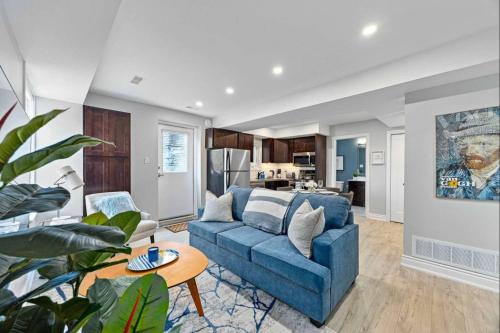a living room with a blue couch and a kitchen at Casa St Clair - Family Suite w Patio in Toronto