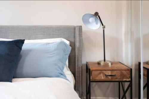 a lamp on a night stand next to a bed at Casa St Clair - Family Suite w Patio in Toronto