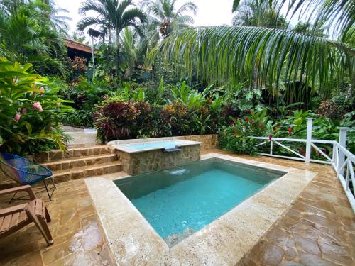 a pool in the middle of a garden with trees at FLOR DE PARAISO BUNGALOWS in Montezuma
