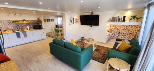 a living room with two green couches and a kitchen at Casa Canes - Beachfront Doggy Living! in Ensenada
