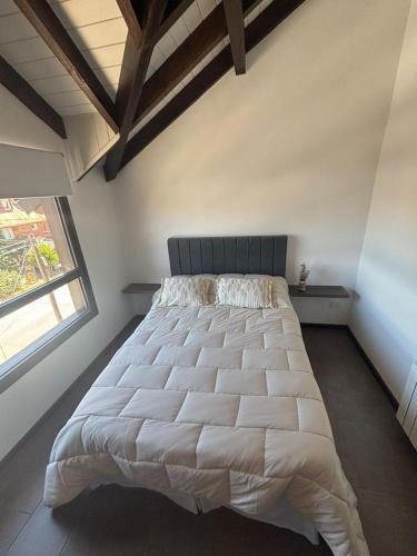 a large bed in a bedroom with a window at Centrico y cómodo Depto en San Martin de los Andes in San Martín de los Andes
