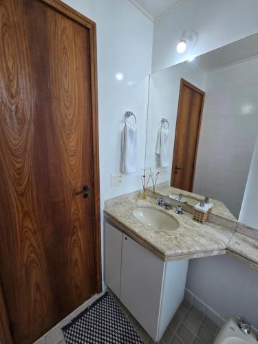 a bathroom with a sink and a wooden door at Volpi Residence Savassi - VIP - Sinta-se em casa in Belo Horizonte