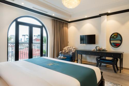 a bedroom with a bed and a desk and a balcony at Hanoi Bliss Hotel in Hanoi