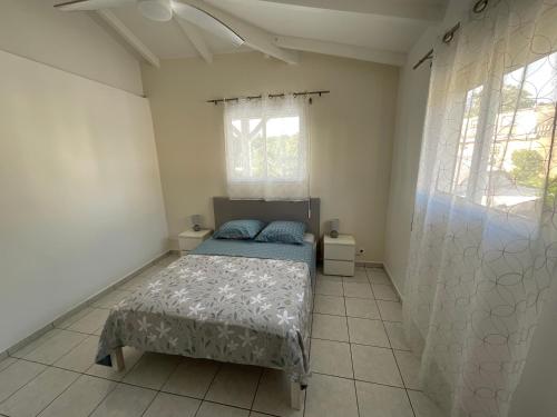 a bedroom with a bed and two windows at Location Les Flamboyants in Sainte-Anne