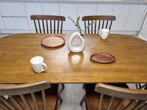 a wooden table with two cups and a pitcher on it at Wanna Stay in Suwon