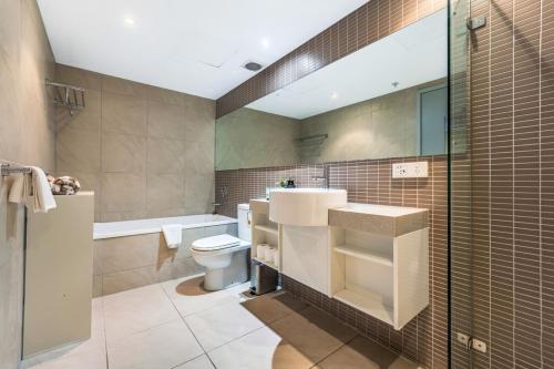 a bathroom with a sink and a toilet and a tub at Stunning City Views from Modern 1BR Apartment King in Darwin
