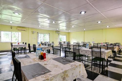 a dining room with tables and chairs in a building at Townhouse OAK Gorumara Jungle Resort in Chālsa Mahābāri