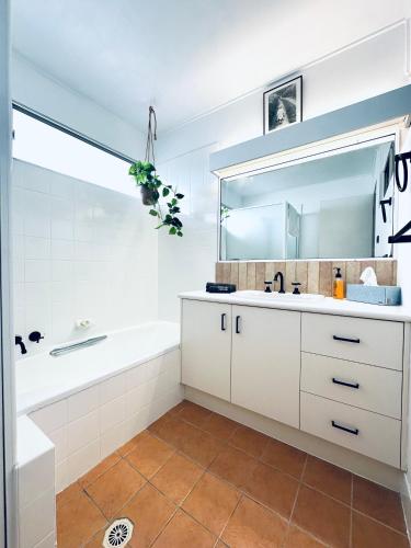 a bathroom with a sink and a tub and a mirror at 3 bedrooms with Views over Kirra! in Gold Coast