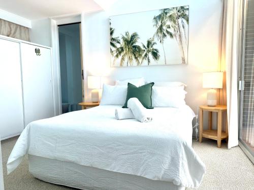 a bedroom with a white bed with white sheets and green pillows at 3 bedrooms with Views over Kirra! in Gold Coast