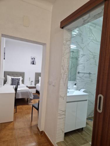 a bathroom with a shower and a sink and a bed at Residencial Antonio Mocisso Guesthouse in Elvas