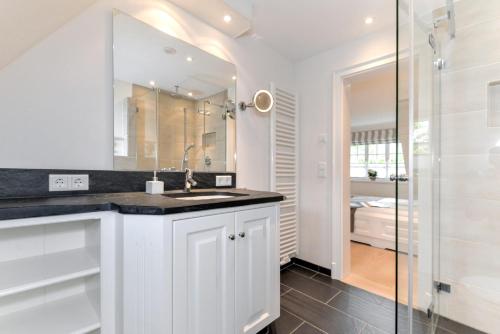 a white bathroom with a sink and a shower at LITZKOW 12802 in Morsum