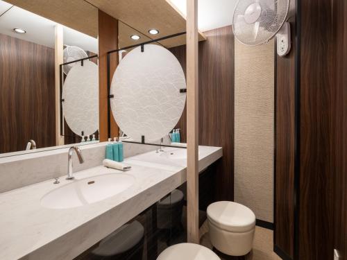 a bathroom with two sinks and a toilet and two mirrors at APA Hotel Akabane Iwabuchi Ekimae in Tokyo