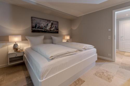 una camera da letto bianca con un grande letto con lenzuola bianche di LITZKOW 16205 ad Archsum