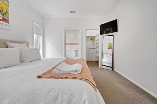 a white bedroom with a bed with a towel on it at Mountain Vista Retreat - Comfort Meets Style in Lake Albert