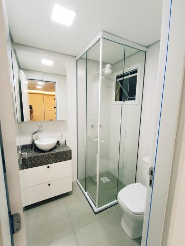 a bathroom with a glass shower and a toilet at Apto em frente a piscina no centro de Pelotas in Pelotas