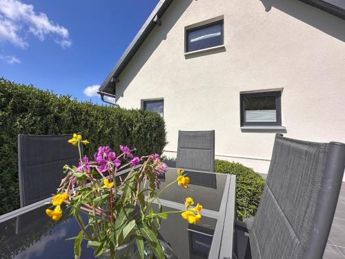 a patio with two chairs and a vase of flowers at Freistehendes Haus mit Ofen, Terrasse und Garten in Stadlern