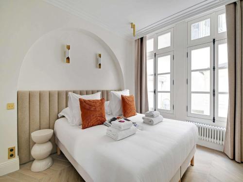 une chambre avec un grand lit blanc avec des oreillers orange dans l'établissement Sublim Apartement Center of Paris Montmartre, à Paris