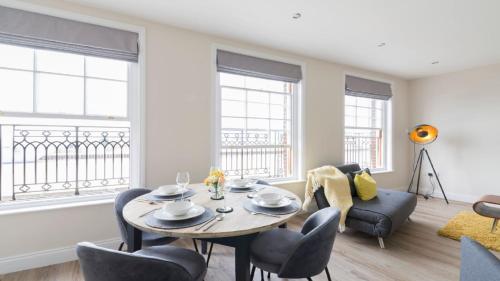 a living room with a table and chairs and windows at South Quay Penthouse - 2 Bed in Great Yarmouth