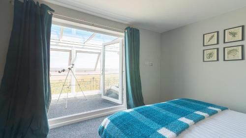 a bedroom with a bed and a large glass window at Marina Beach House in Caister-on-Sea