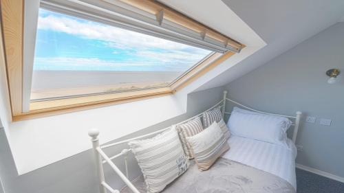Un dormitorio con una cama con una ventana grande. en Marina Beach House, en Caister-on-Sea