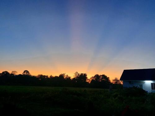 a barn with a rainbow in the sky at sunset at Mai Paddy Cottage, Balik Pulau in Balik Pulau