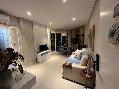a living room with a couch and a tv at Estanconfor Vista Mar em Santos in Santos