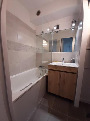 une salle de bain avec une baignoire, un lavabo et un miroir dans l'établissement Apartment Renovated Cosy 6 pers, à Les Deux Alpes