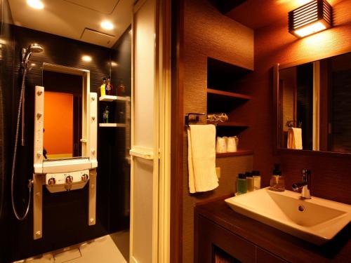 a bathroom with a sink and a shower at Arima Hot Spring Ryokan Hanamusubi in Kobe