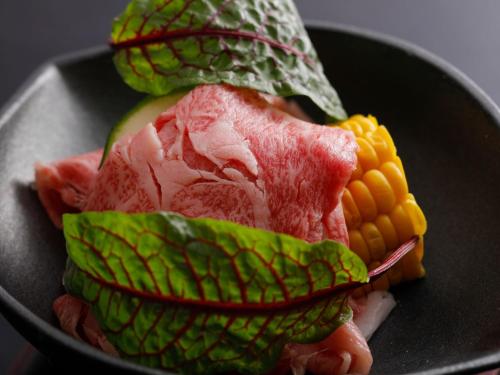 a plate of food with meat and corn on the cob at Arima Hot Spring Ryokan Hanamusubi in Kobe